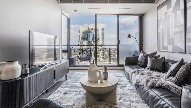 Ein modernes Wohnzimmer mit großem Fenster, einer Couch, einem Couchtisch und einem Fernseher.