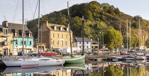 A harbor with boats, a building with a green facade, and a hill in the background. - Charming new house with terrace, Port du Legue (Plérin)