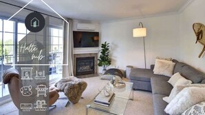 A modern living room with a fireplace, a sofa, a coffee table, and a large window.