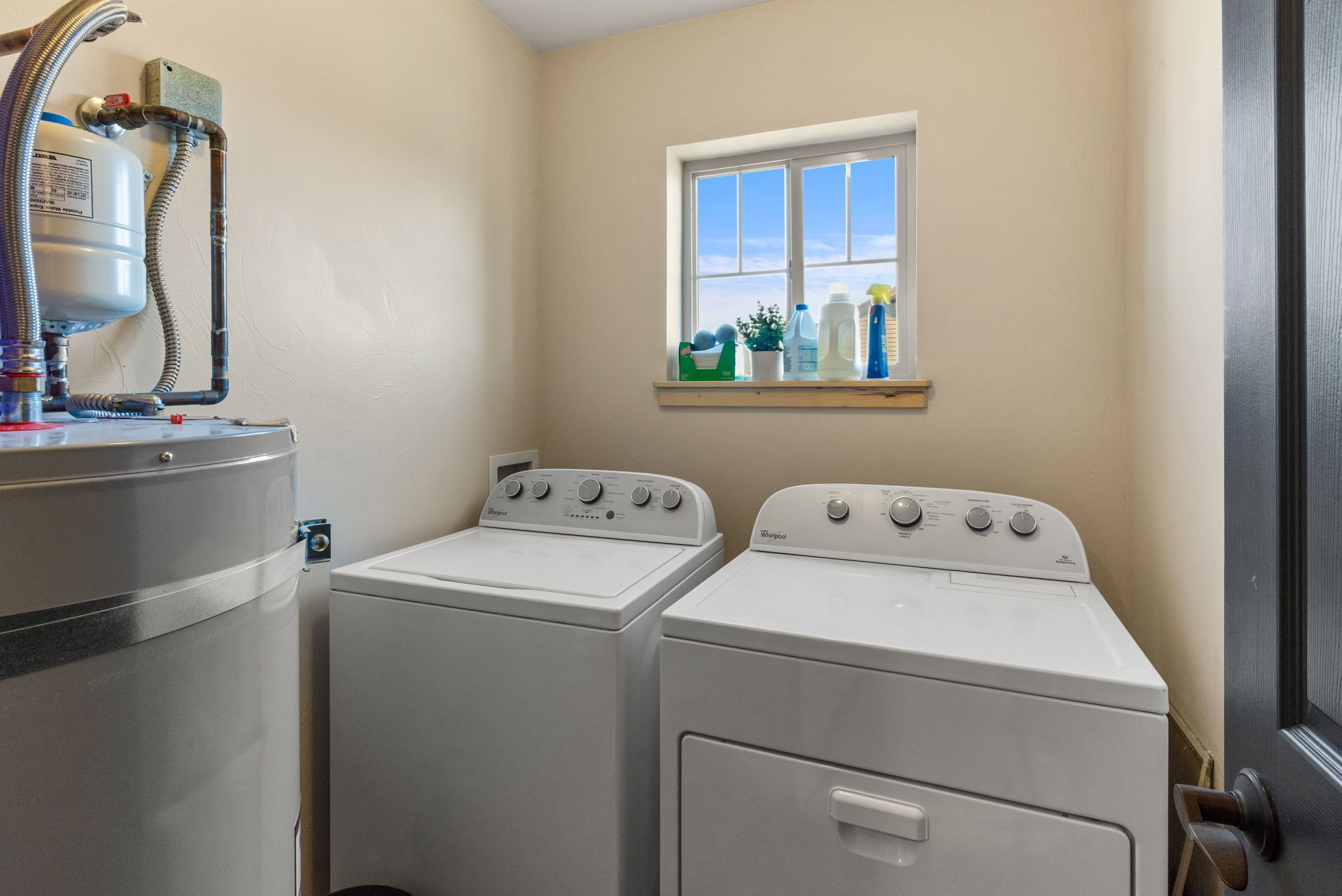 A laundry area with two front-loading washers and a water heater.