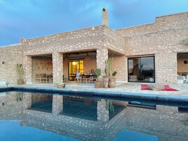 Una piscina al aire libre, sombrillas, sillones reclinables de piscina