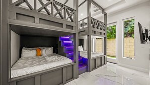 Une chambre moderne avec des lits superposés, un escalier et une vue sur l’extérieur.