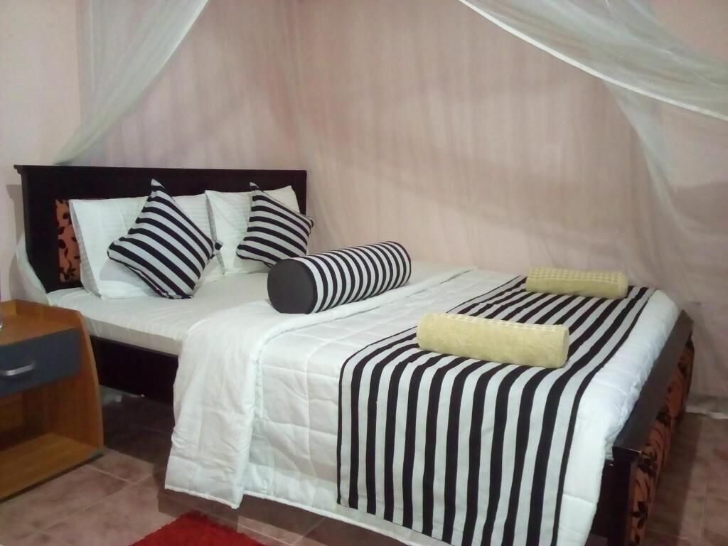Una cama con dosel, ropa de cama a rayas y una mesita de noche.