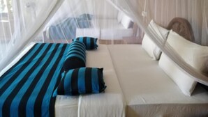 A bed with a canopy, pillows, and a bedside table. - Blue Ribbon Homestay  (Ella)
