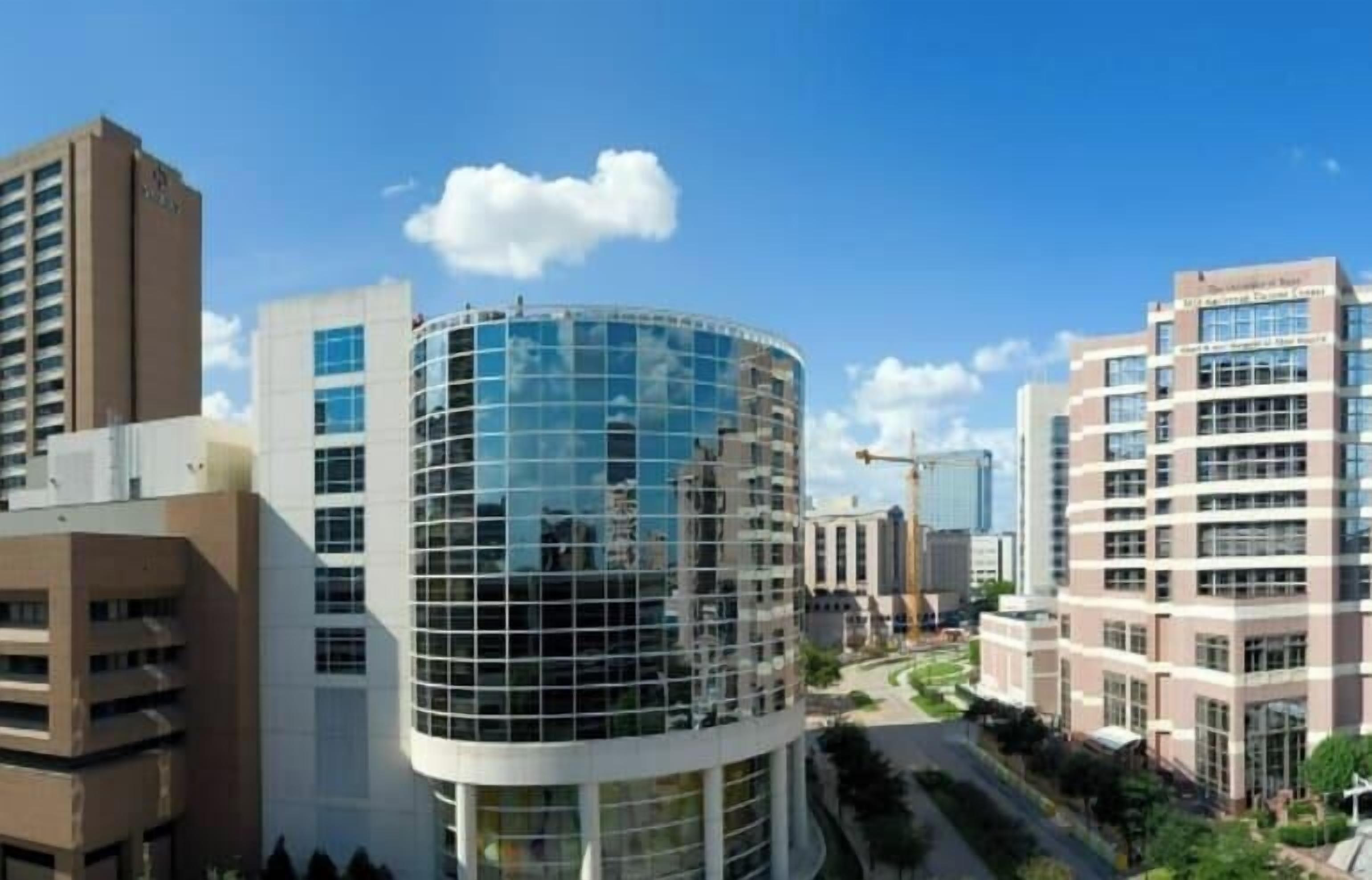 A modern building with a curved glass facade, surrounded by other high-rise structures.