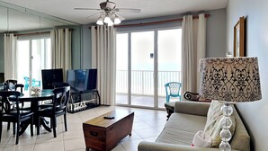 A living room with a TV, sofa, coffee table, and a balcony with curtains.