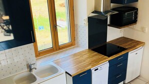 A modern kitchen with a wooden countertop, white cabinets, and a built-in microwave.