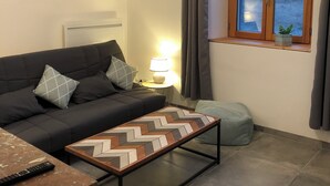A modern living room with a sofa, a coffee table, a lamp, and a window with curtains.
