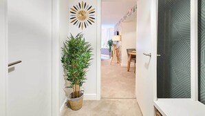 A hallway with a potted plant, a decorative wall clock, and a patterned door.