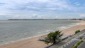 Una playa con un paseo pavimentado y vista al océano.