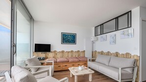 Una sala de estar moderna con un sofá, sillas, una mesa de centro y un televisor.