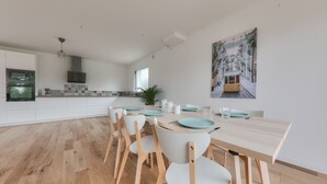 A modern kitchen with white cabinets, a wooden dining table, and chairs. - House for 8 - 300m from Rouvran beach (Le Tour-du-Parc)