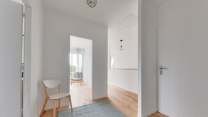 A hallway with a wooden floor, a white chair, and a grey rug. - House for 8 - 300m from Rouvran beach (Le Tour-du-Parc)