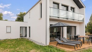 A modern two-story house with a balcony, a wooden deck, and a dining area. - House for 8 - 300m from Rouvran beach (Le Tour-du-Parc)
