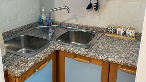 Une cuisine équipée de deux éviers en acier inoxydable, de meubles en bois et d’un plan de travail en granit.