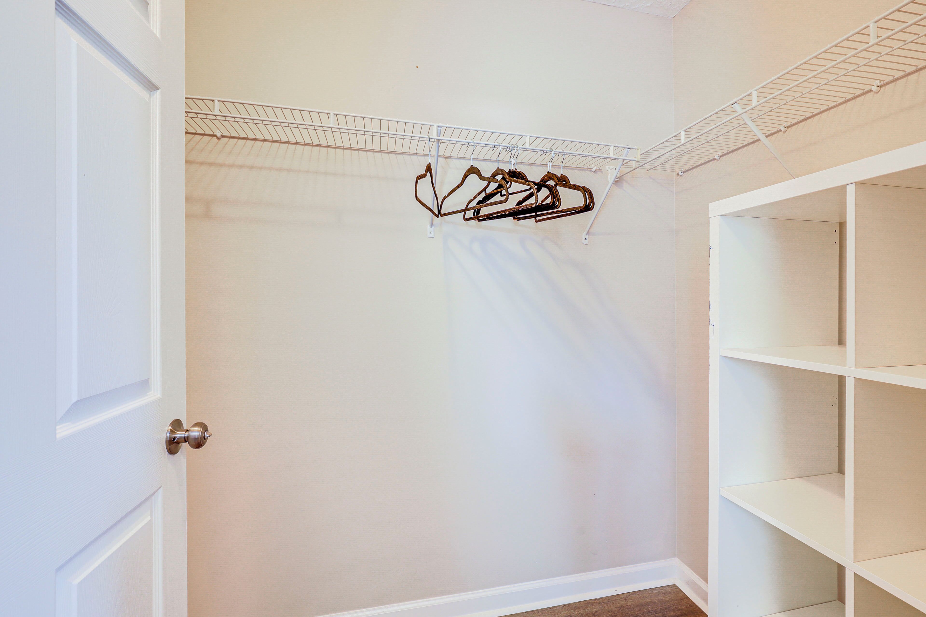 A room with a white door, a metal drying rack, and white shelving units.