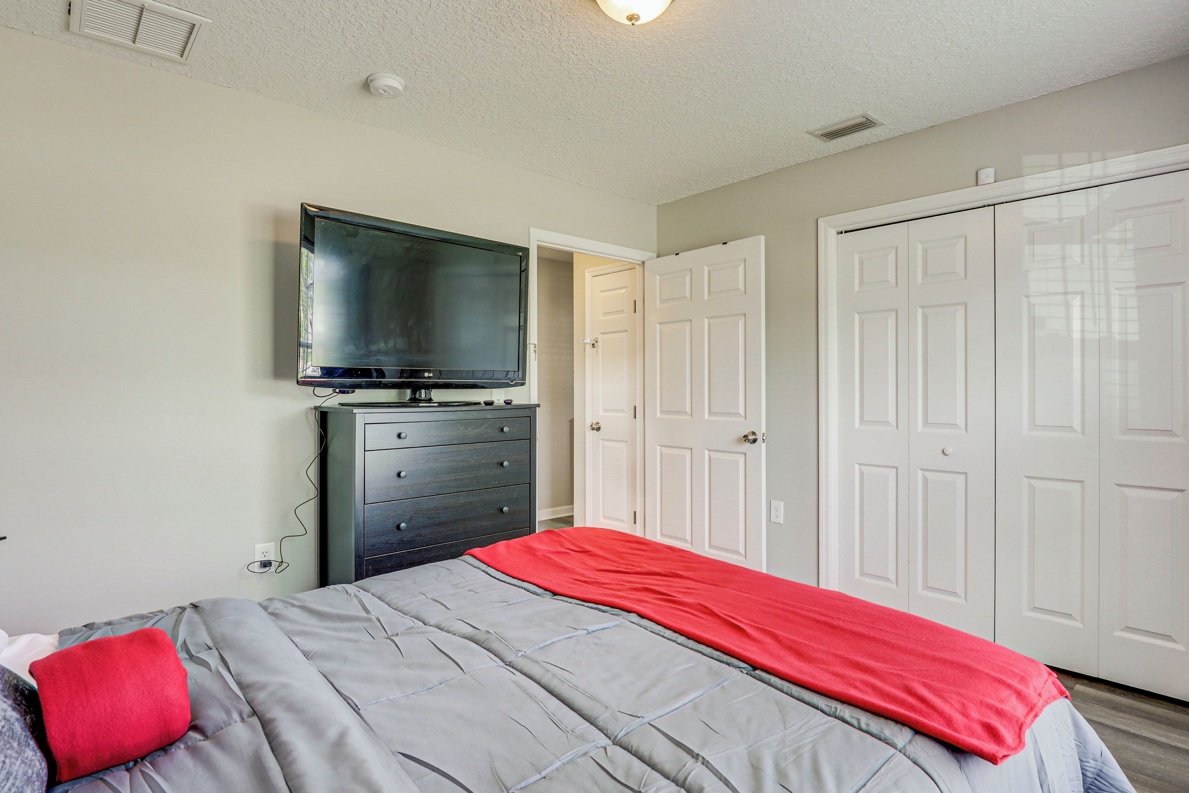 A bedroom with a bed, a dresser, a television, and a closet.