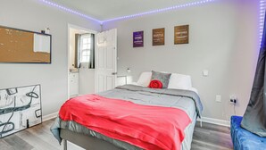 A bedroom with a bed, a corkboard, motivational posters, and LED strip lighting.