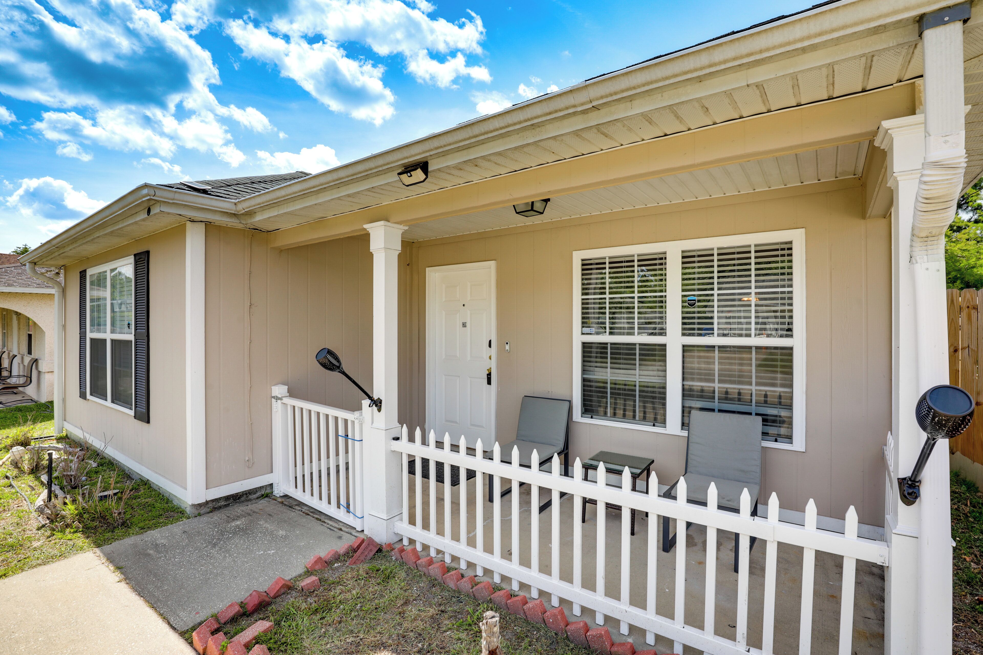 A residential house with a front porch, a white picket fence, and a door.