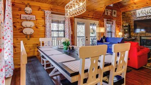 Een houten cabin met een eettafel, stoelen, een bank, een open haard en een televisie.