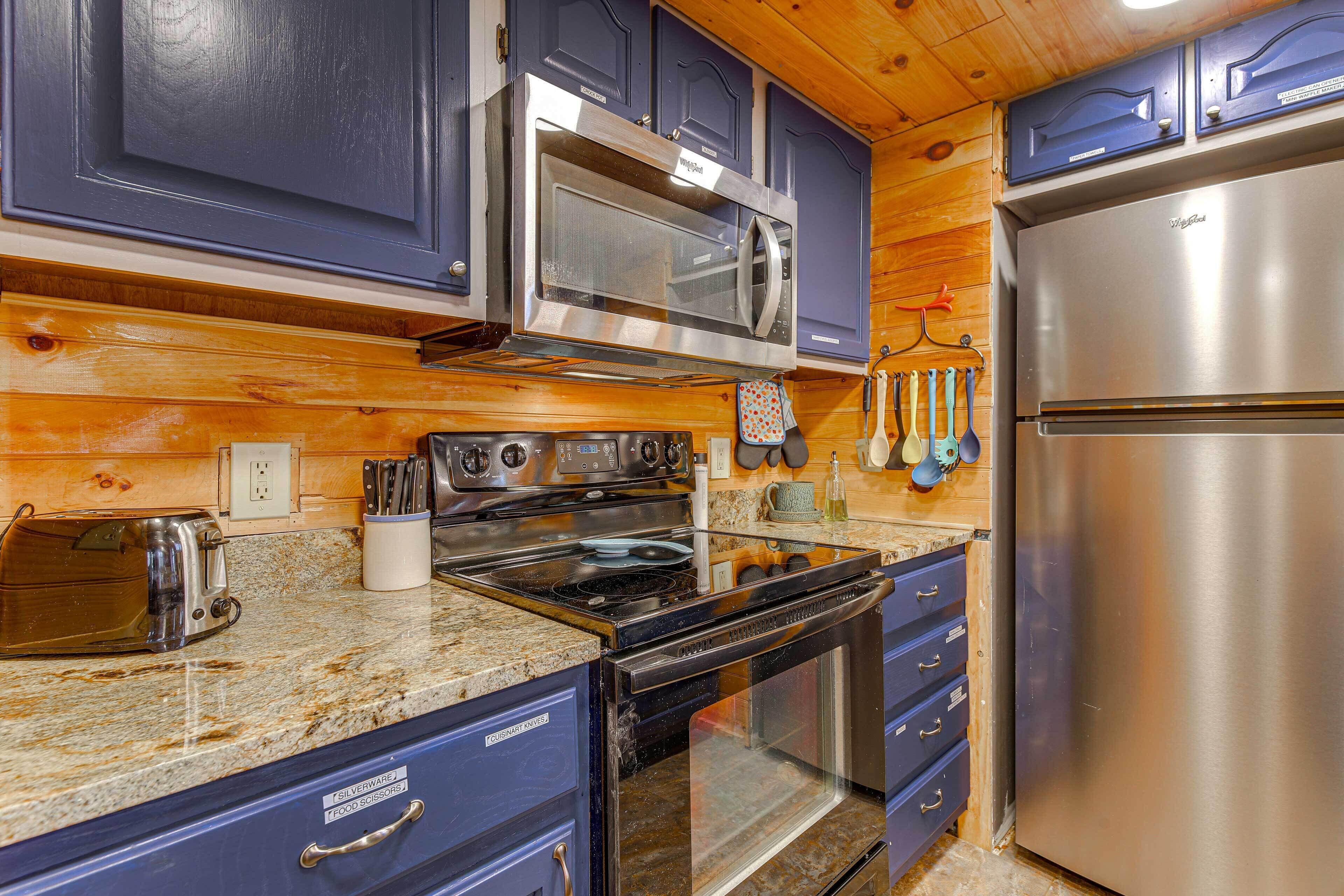 Una cocina con refrigerador de acero inoxidable, microondas, estufa y gabinetes azules.