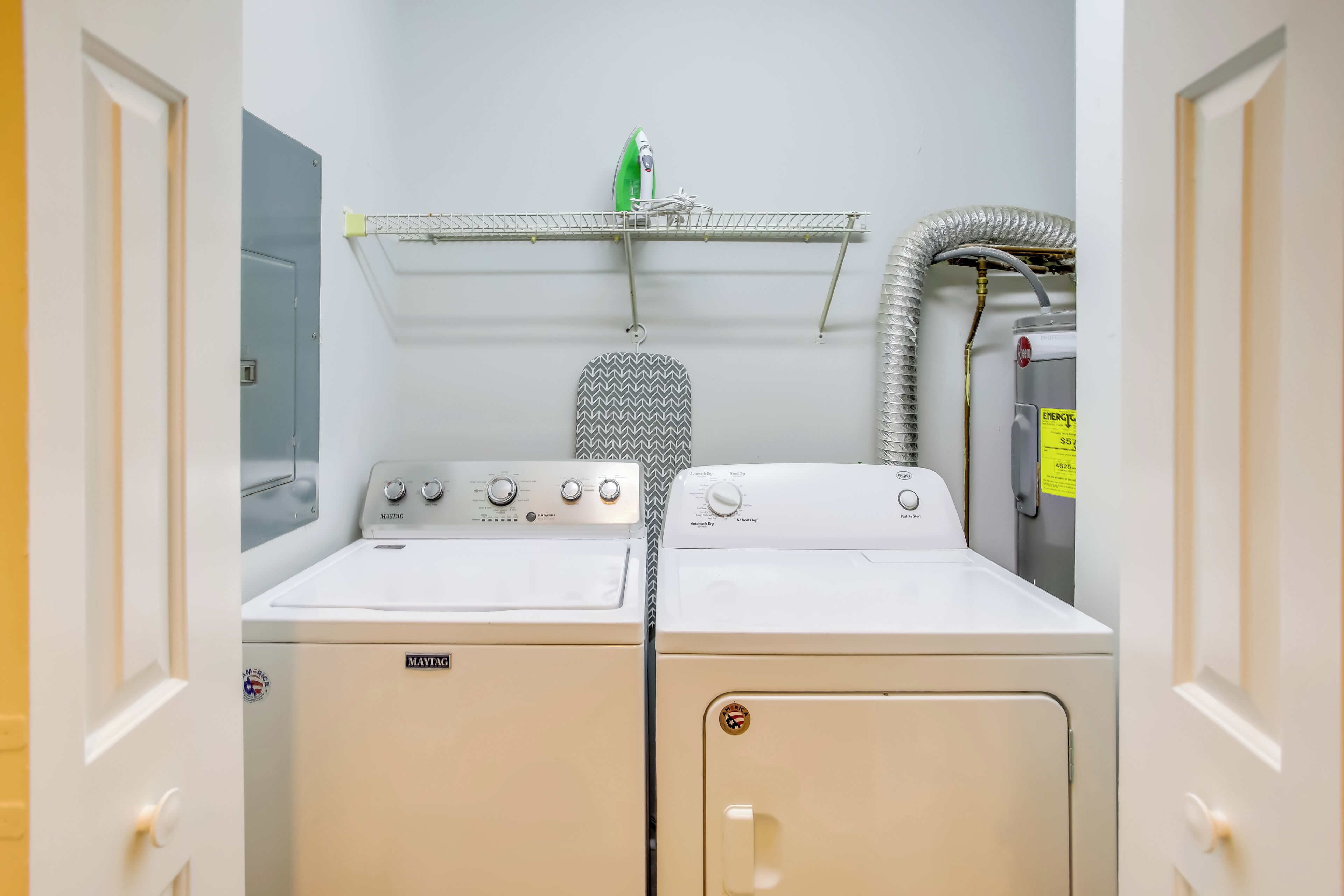 Een wasserette met twee Maytag wasmachines en drogers, een droogrek en een boiler.