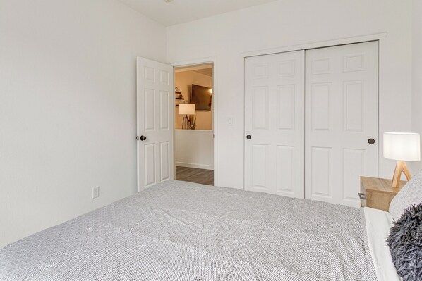 A bedroom with a large bed, white walls, and a door leading to another room. - Seasonal Pool, Balcony: Quiet & Cozy Aurora Condo! (Aurora)