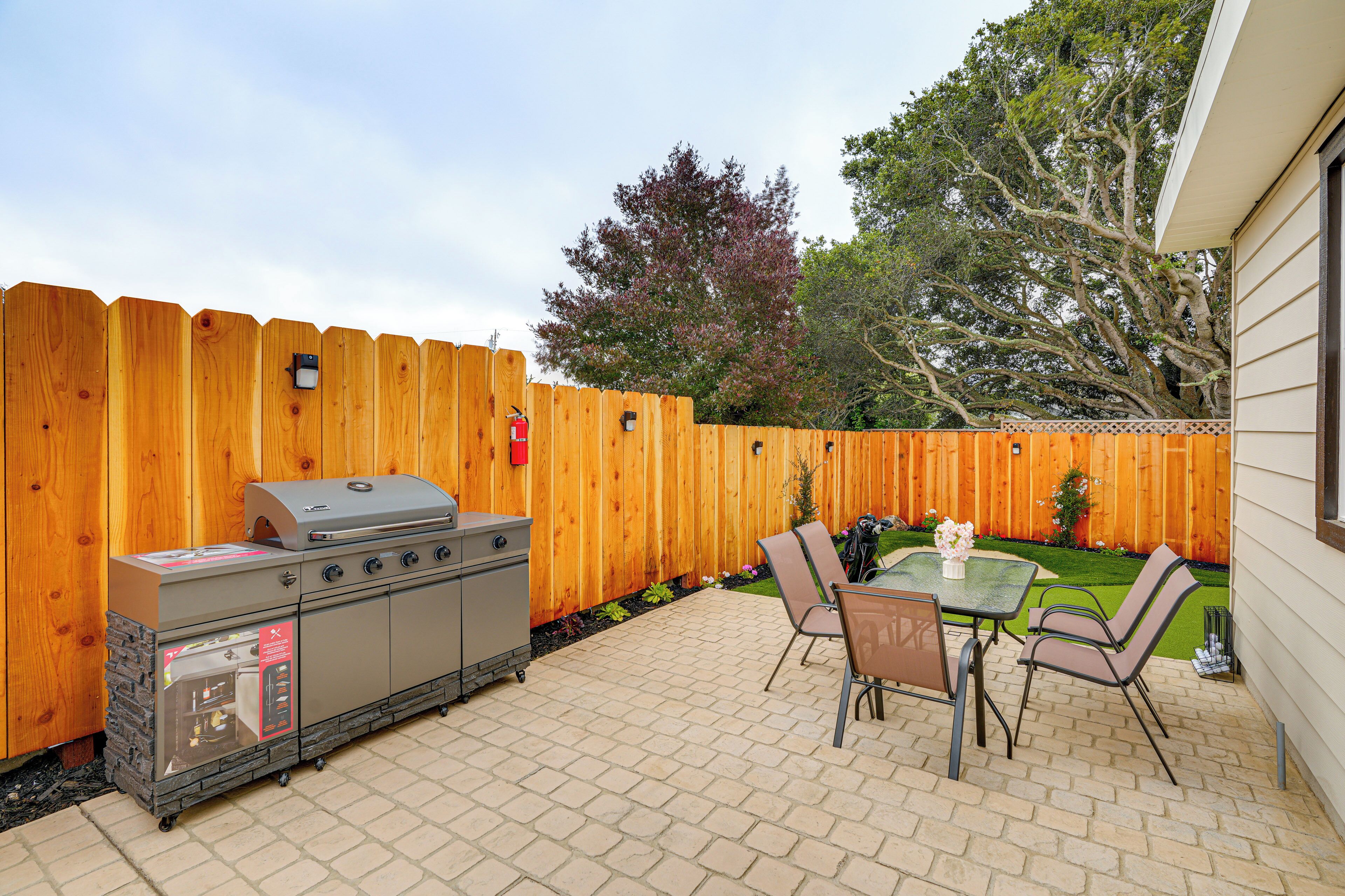 Une terrasse extérieure avec un barbecue, des chaises et une table.