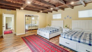 A bedroom with wooden beams, a red patterned rug, two beds with checkered bedding, a white dresser, and a mirror. - Del Rey Oaks Vacation Home w/ Mini-golf Course! (Monterey)