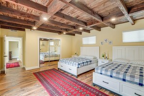 A bedroom with wooden beams, a red patterned rug, two beds with checkered bedding, a white dresser, and a mirror. - Del Rey Oaks Vacation Home w/ Mini-golf Course! (Monterey)