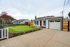 A residential property with a well-maintained lawn, a garage, and a brick driveway. - Del Rey Oaks Vacation Home w/ Mini-golf Course! (Monterey)