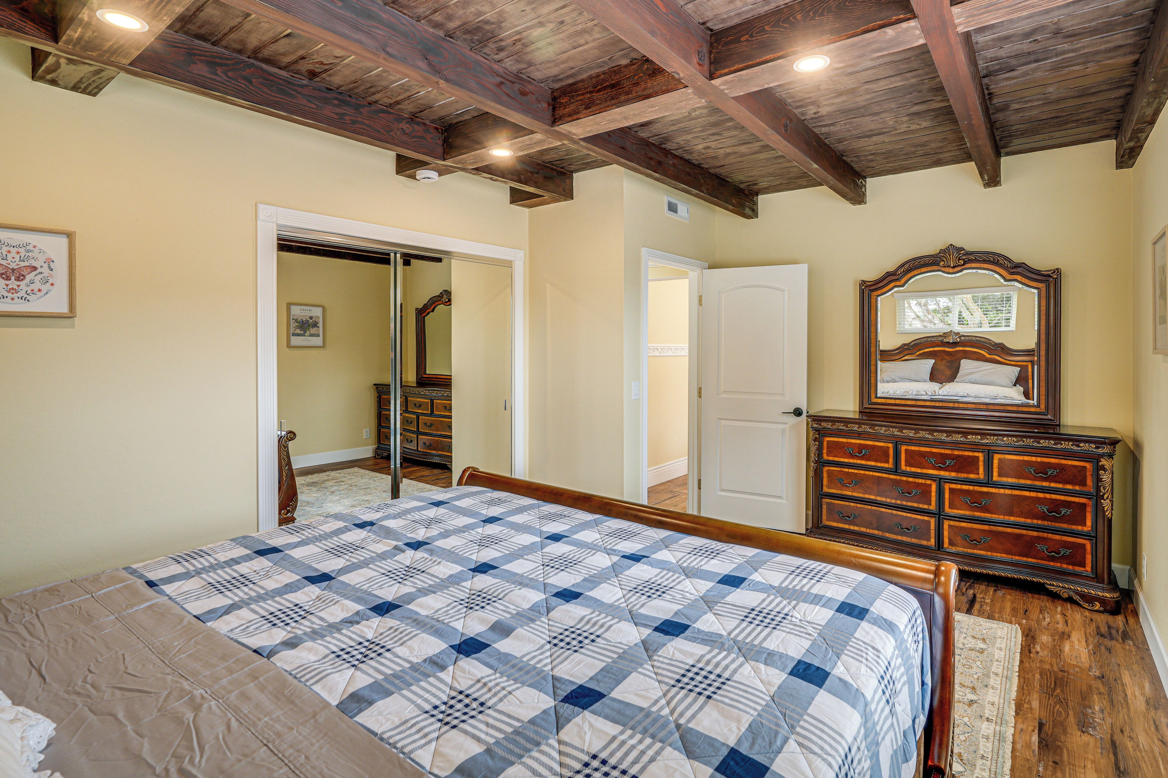 Un dormitorio con cama, cómoda de madera y espejo.