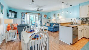 A modern kitchen with white cabinets, a central island, and pendant lights. - Carolina Beach Condo w/ Balcony: Walk to the Ocean (Carolina Beach)