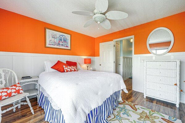 A bedroom with a bed, white furniture, a ceiling fan, a door, and a dresser. - Carolina Beach Condo w/ Balcony: Walk to the Ocean (Carolina Beach)