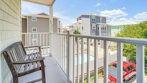 A balcony with a wooden bench, a pool, and a red truck parked nearby. - Carolina Beach Condo w/ Balcony: Walk to the Ocean (Carolina Beach)