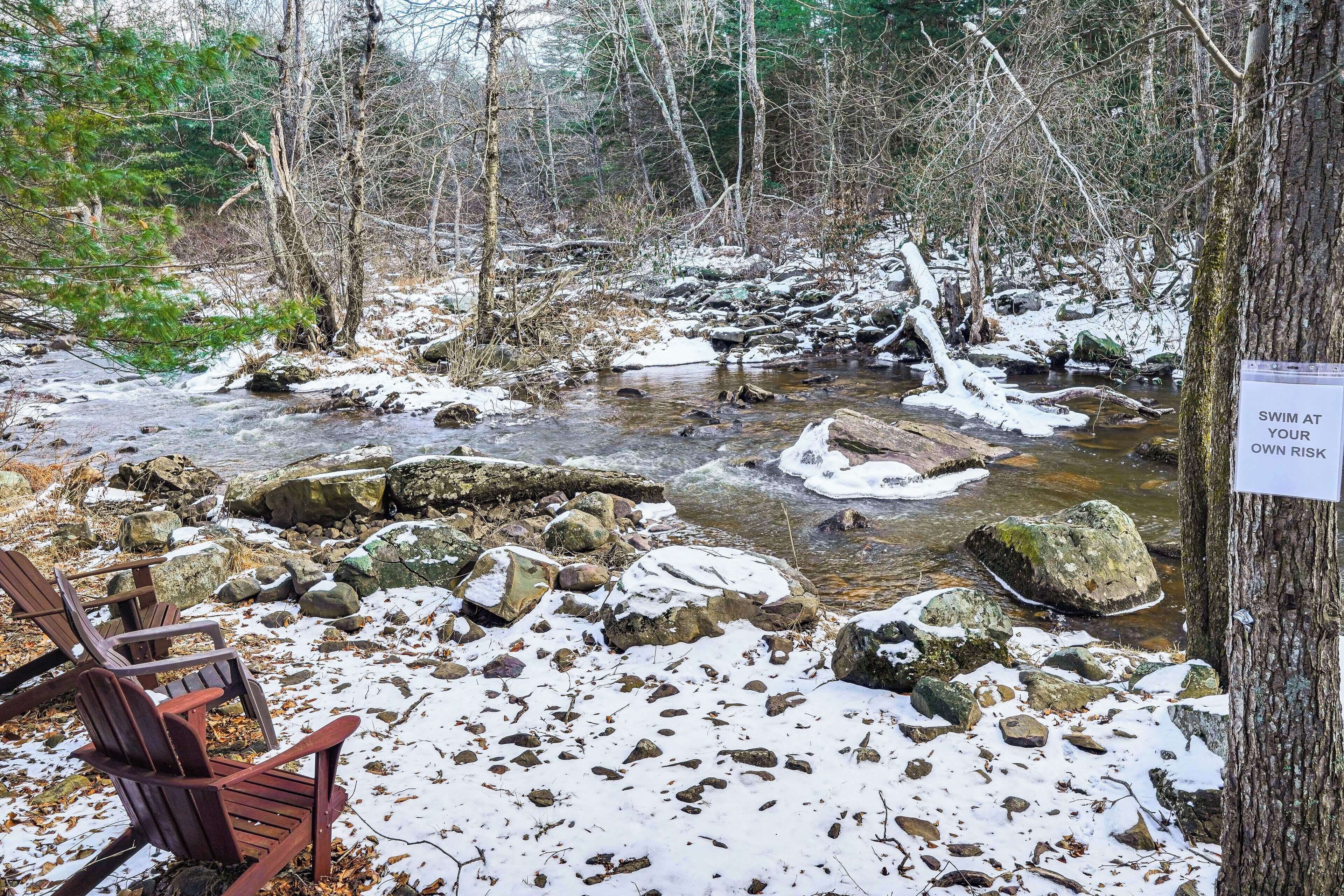 A natural setting with a stream, rocks, and a chair.