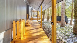 A covered wooden walkway leading to a deck area with a view of a forested landscape. - Creek Access & Deck: Family Pocono Pines Cottage (Pocono Pines)