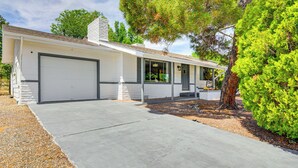 Een gelijkvloers huis met garage, een overdekte veranda en een verzorgd gazon.