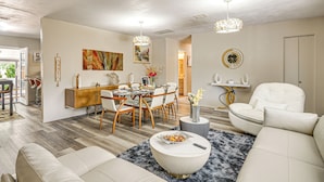 Een moderne woonkamer met een eethoek, met een bank, eettafel, stoelen en een decoratieve vaas.