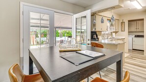 Een moderne keuken met een eetgedeelte, met een groot raam, een inbouwoven en een hanglamp.