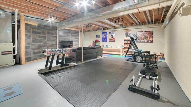 A spacious room with a foosball table, exercise equipment, and posters on the wall.