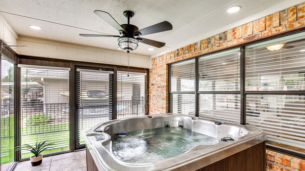 A hot tub in a room with a ceiling fan, large windows, and a brick wall. - Home on Lake Granbury w/ Hot Tub: 5 Mi to Dtwn! (Granbury)