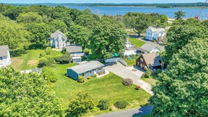 A residential area with houses, green lawns, and a body of water in the background. - Old Saybrook Home w/ Screened Porch & Ocean View! (Old Saybrook)