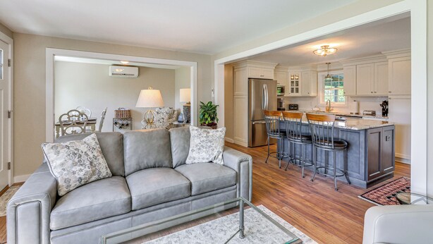 A modern kitchen with a central island, bar stools, and a dining area with a table and chairs. - Old Saybrook Home w/ Screened Porch & Ocean View! (Old Saybrook)