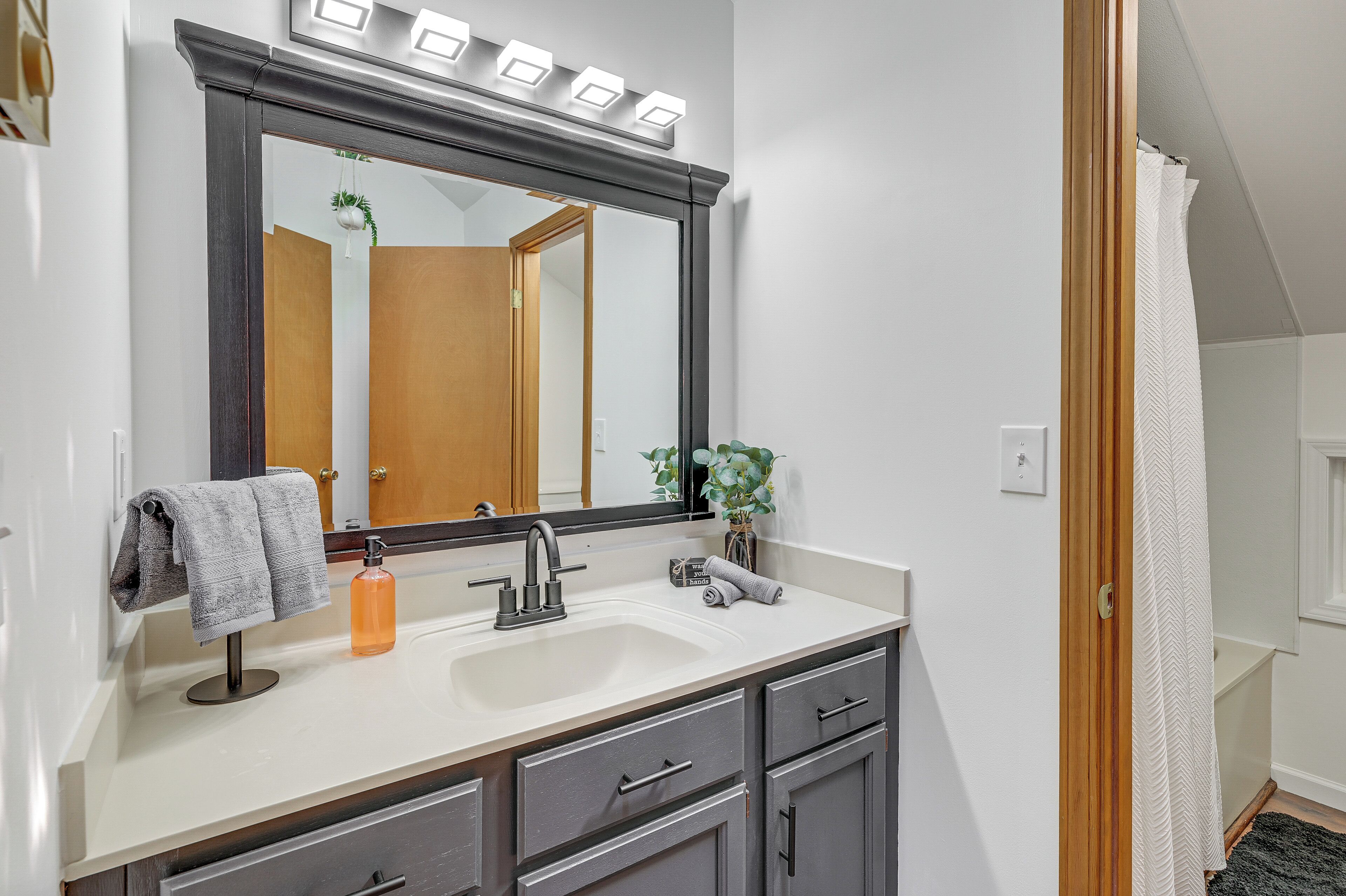 A bathroom with a large mirror, a sink, and a towel rack.