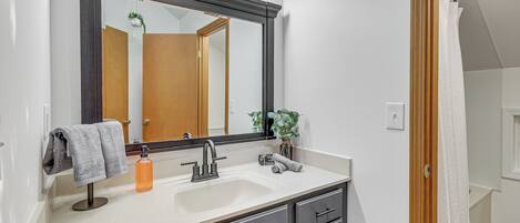 A bathroom with a large mirror, a sink, and a towel rack.