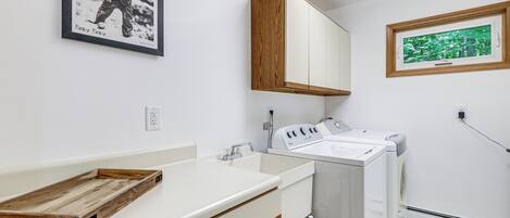 A modern bathroom with a wooden vanity, a built-in washing machine, and a framed photograph on the wall.