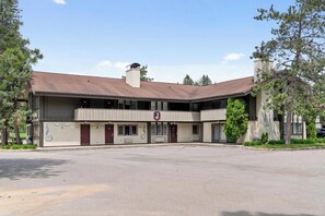A two-story building with a central entrance, large windows, and a parking lot in front.
