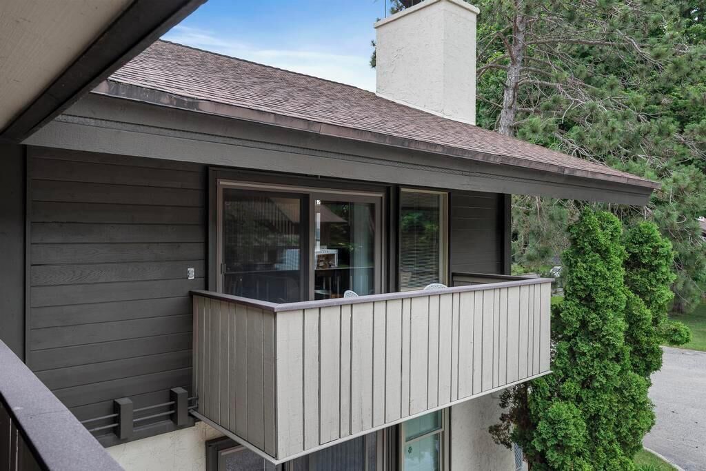 Une maison moderne avec un balcon, une cheminée et un arbre en arrière-plan.