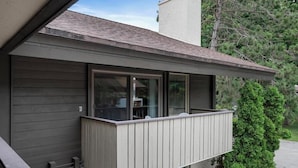 A modern house with a balcony, a chimney, and a tree in the background. - Boyne Mountain Cozy Winter Cabin!  Sleeps 6!  Right at base of Mountain (Boyne Falls)